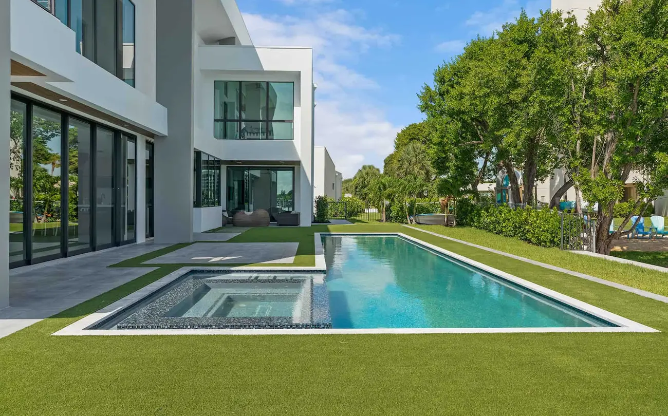 In-ground pool and lawn in the backyard of a luxury modern home.