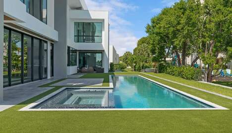 In-ground pool and lawn in the backyard of a luxury modern home.