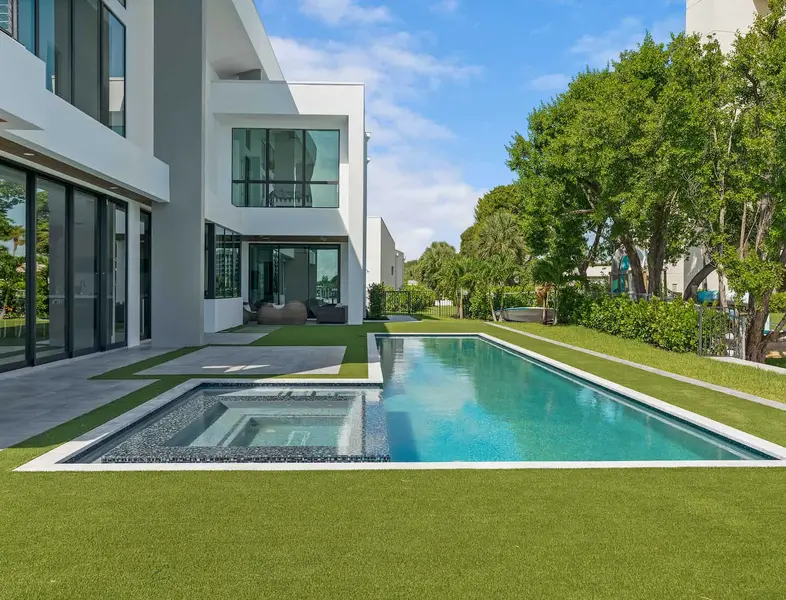 In-ground pool and lawn in the backyard of a luxury modern home.