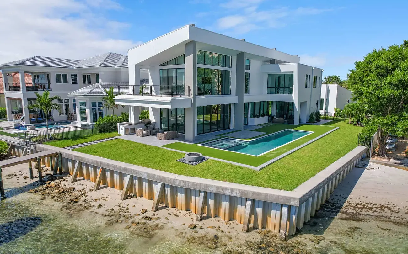 Modern home with large wraparound lawn and in-ground swimming pool on a waterfront lot in Jupiter Florida.