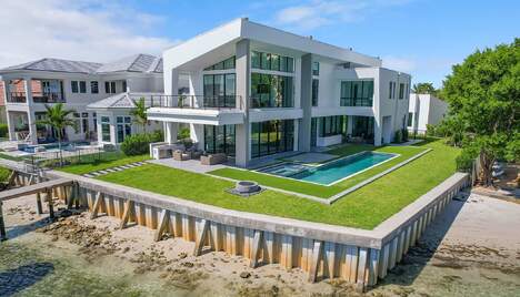 Modern home with large wraparound lawn and in-ground swimming pool on a waterfront lot in Jupiter Florida.
