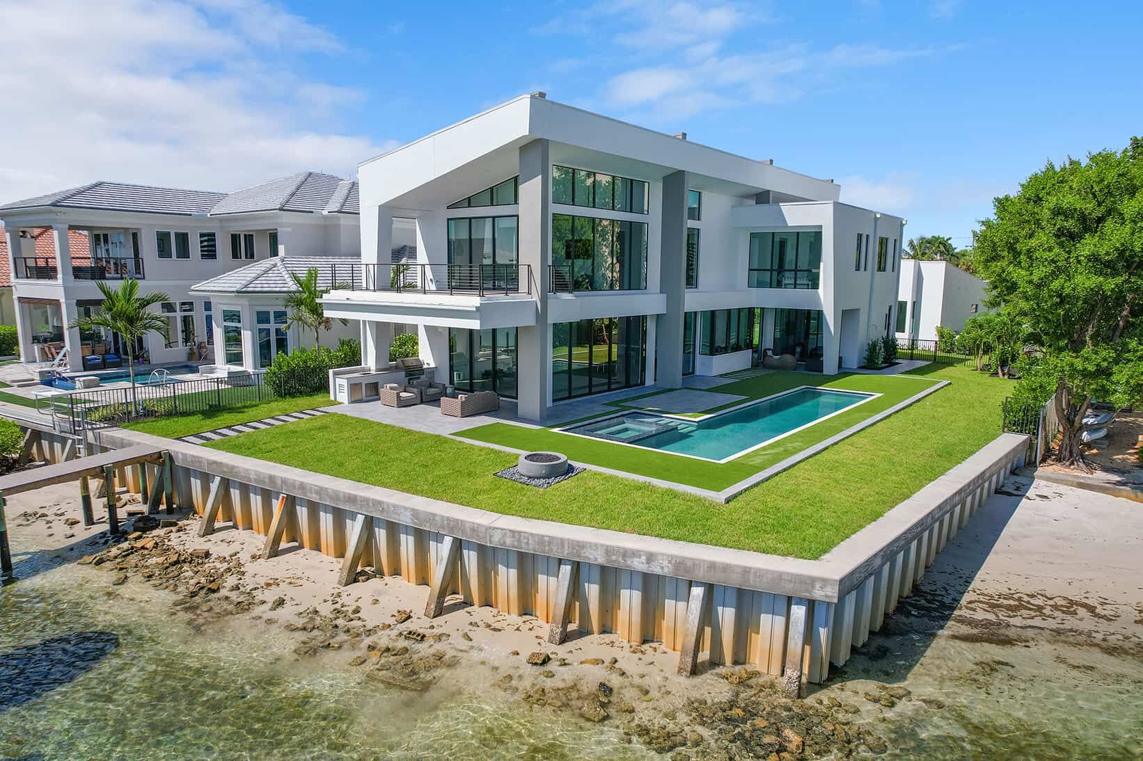 Modern home with large wraparound lawn and in-ground swimming pool on a waterfront lot in Jupiter Florida.