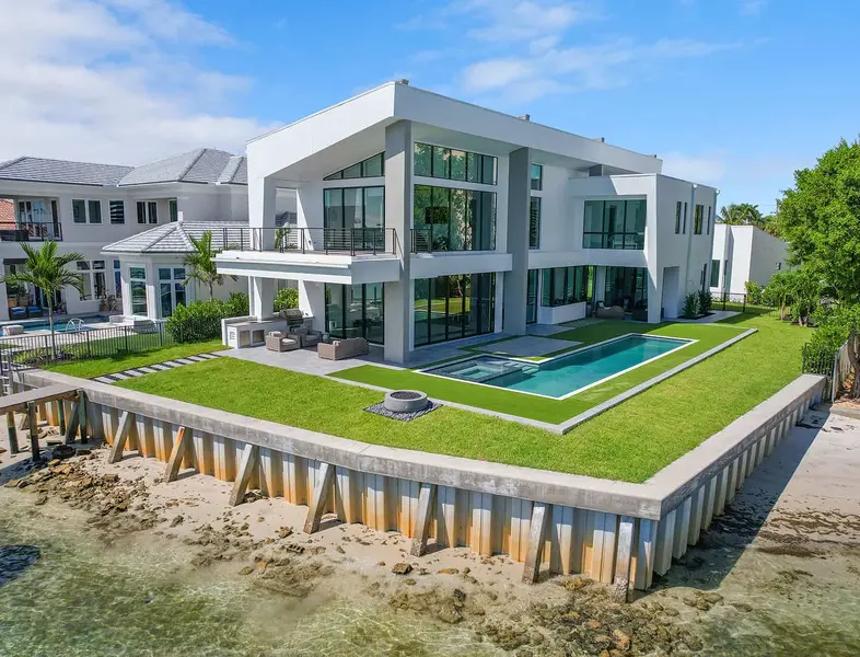 Modern home with large wraparound lawn and in-ground swimming pool on a waterfront lot in Jupiter Florida.