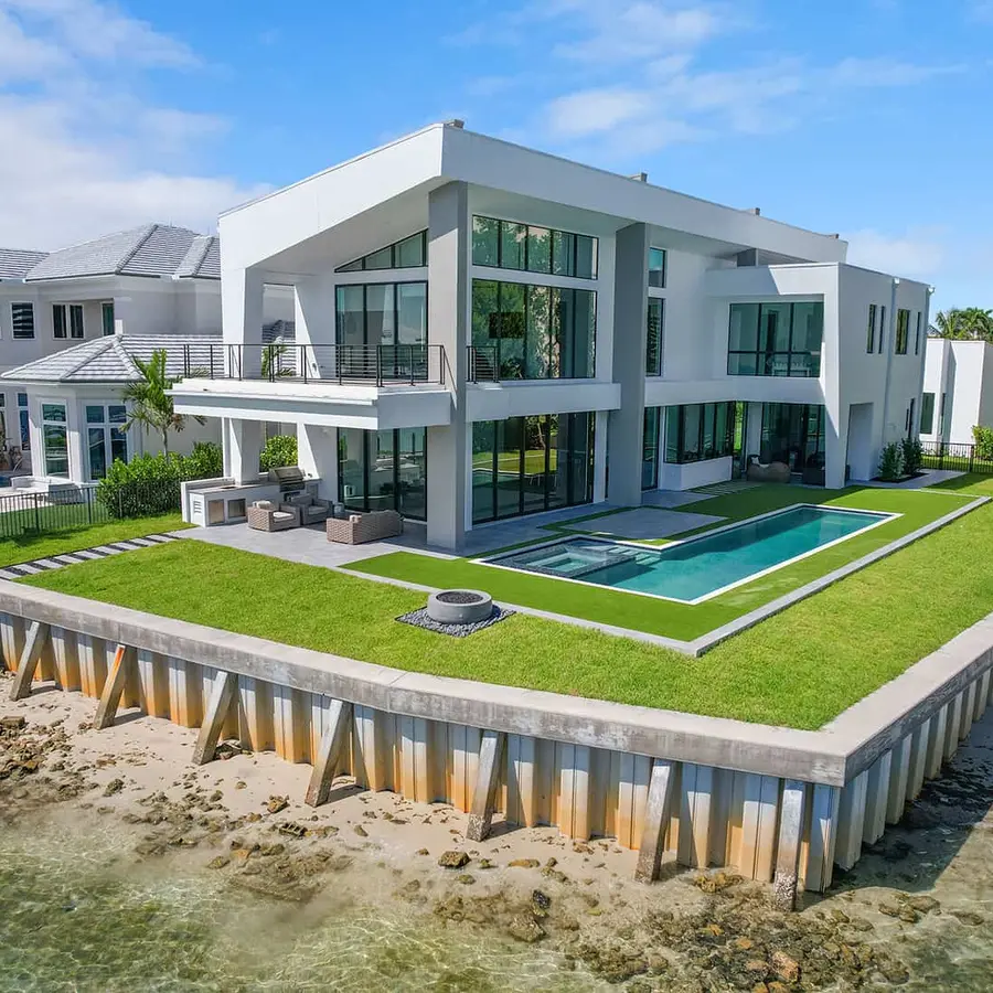 Modern home with large wraparound lawn and in-ground swimming pool on a waterfront lot in Jupiter Florida.