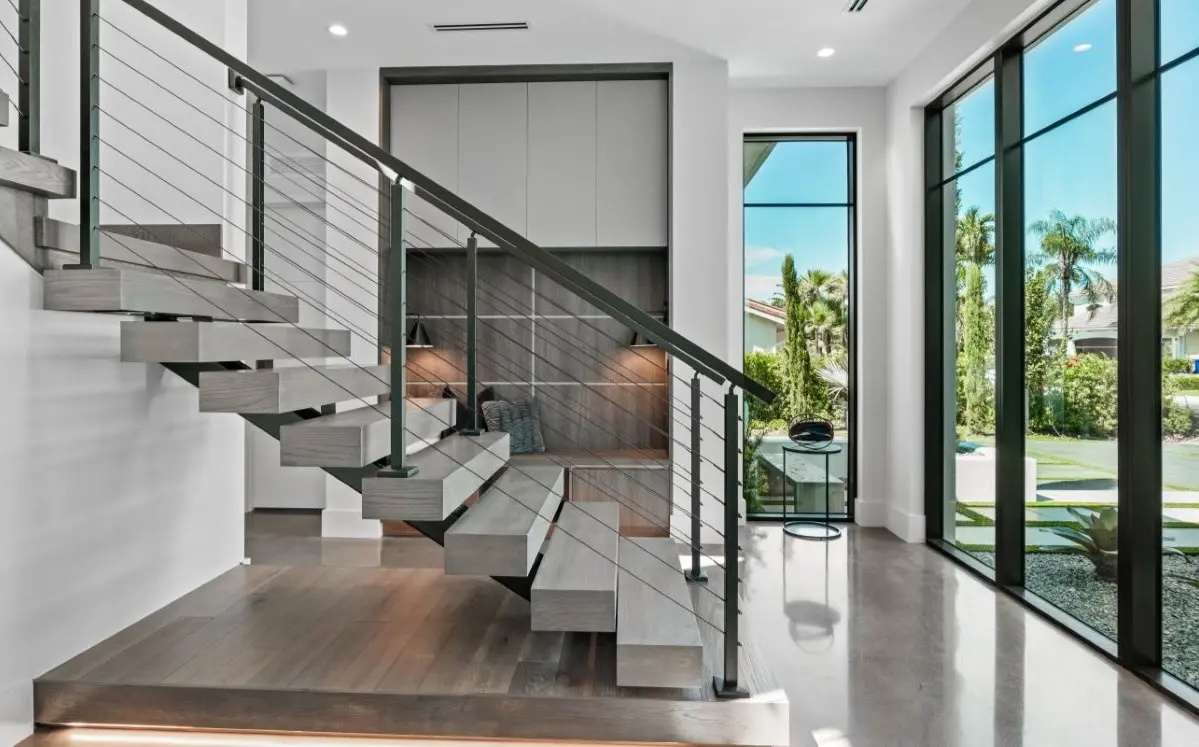 The front entry of a white modern house, glass doors and large stairs.