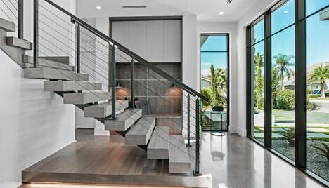 The front entry of a white modern house, glass doors and large stairs.