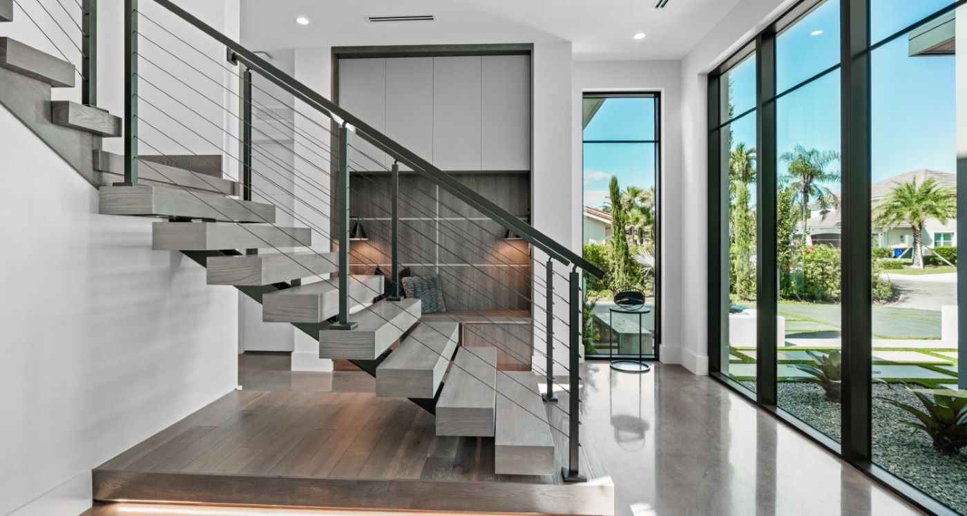The front entry of a white modern house, glass doors and large stairs.