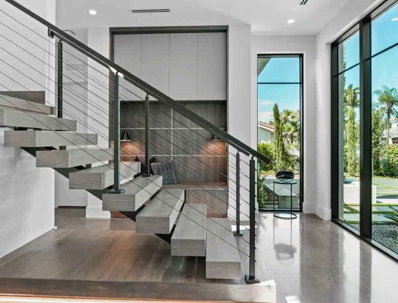 The front entry of a white modern house, glass doors and large stairs.