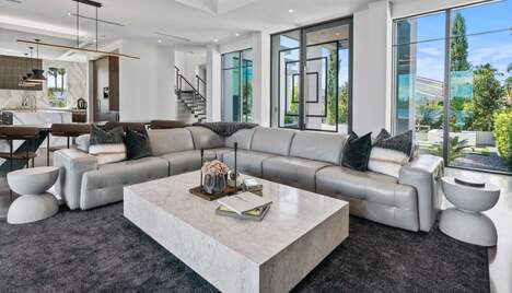 The front room of a white modern house, glass doors and large windows.