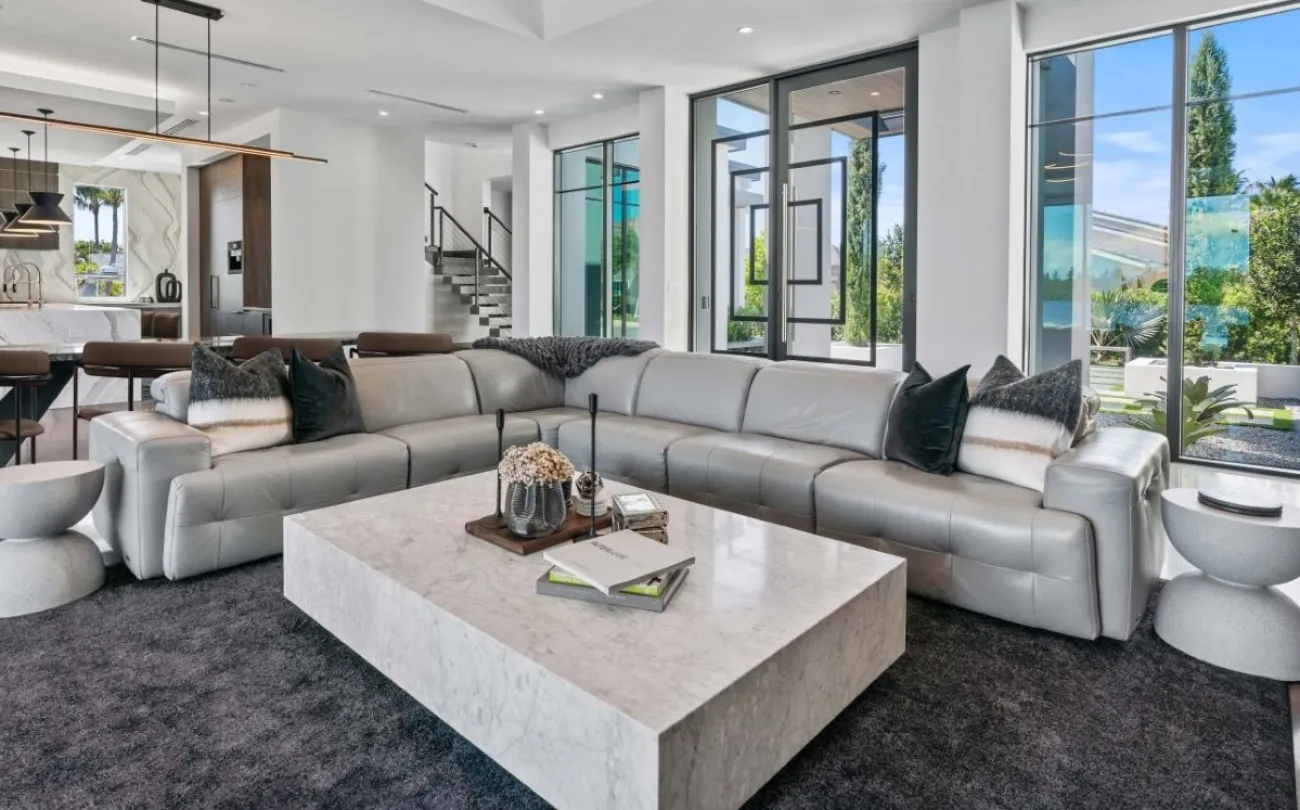 The front room of a white modern house, glass doors and large windows.