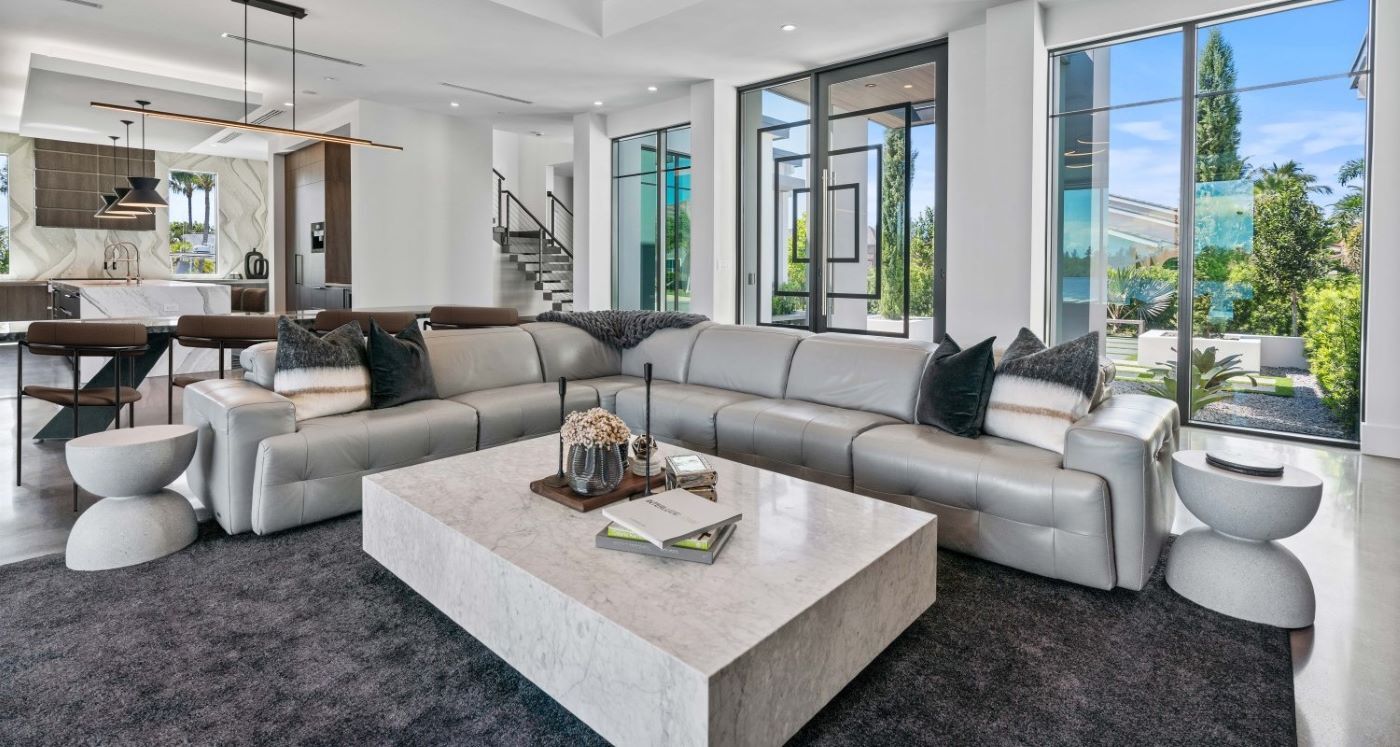 The front room of a white modern house, glass doors and large windows.