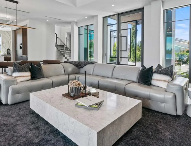 The front room of a white modern house, glass doors and large windows.