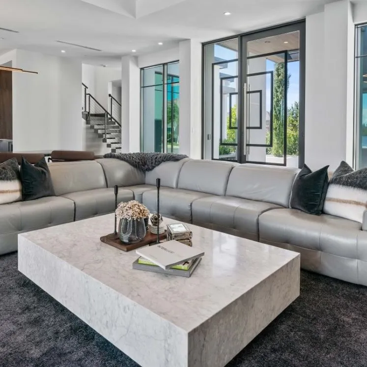 The front room of a white modern house, glass doors and large windows.