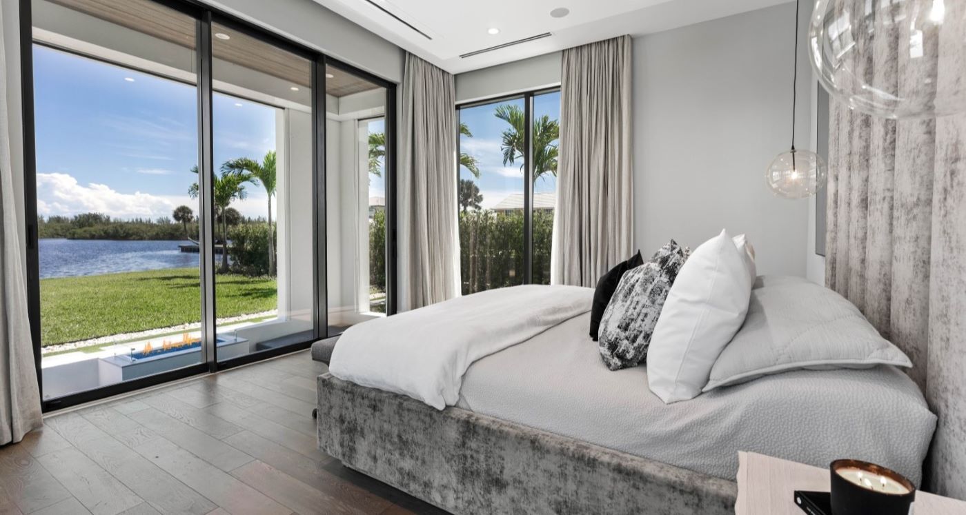 Large luxurious bed in modern home with a wide backyard and a lake.