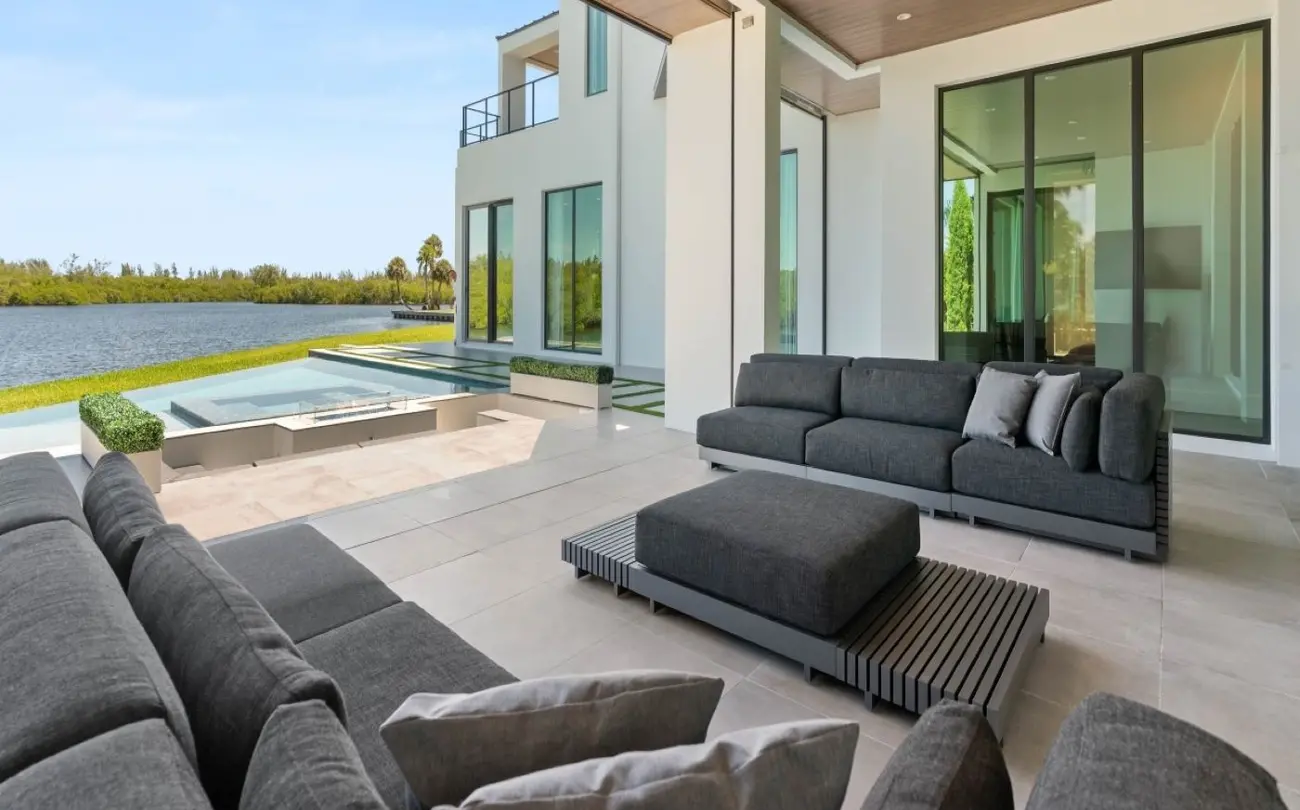 A large outdoor patio with a pool and large windows.