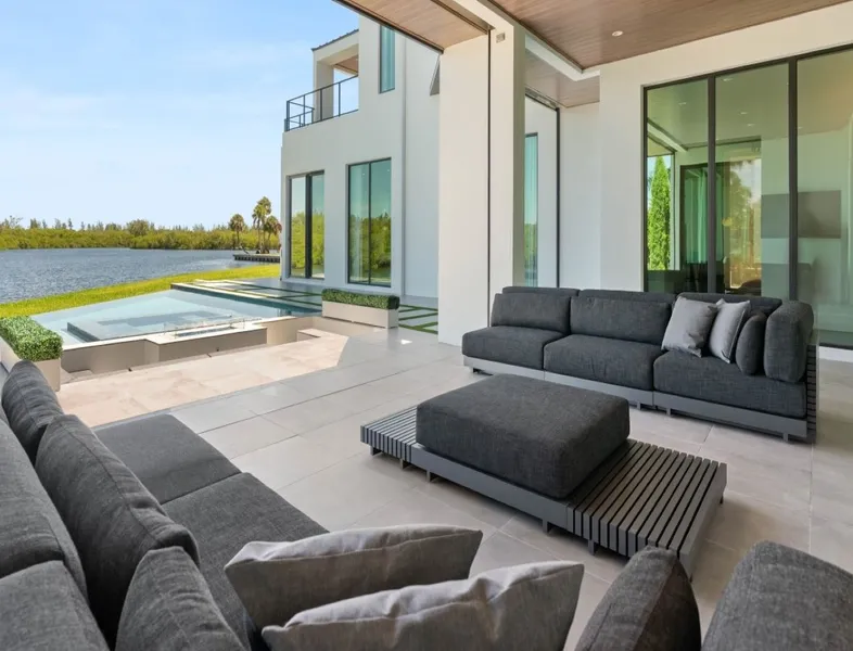 A large outdoor patio with a pool and large windows.