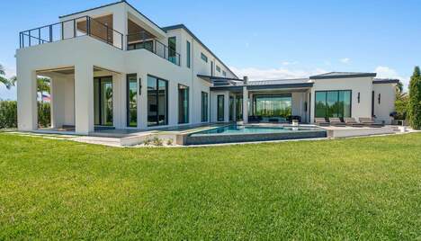 Large white house in modern design with a wide backyard and a pool.