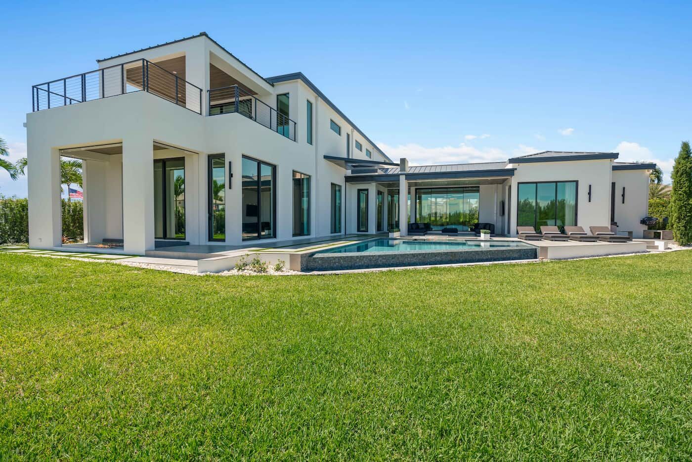 Large white house in modern design with a wide backyard and a pool.