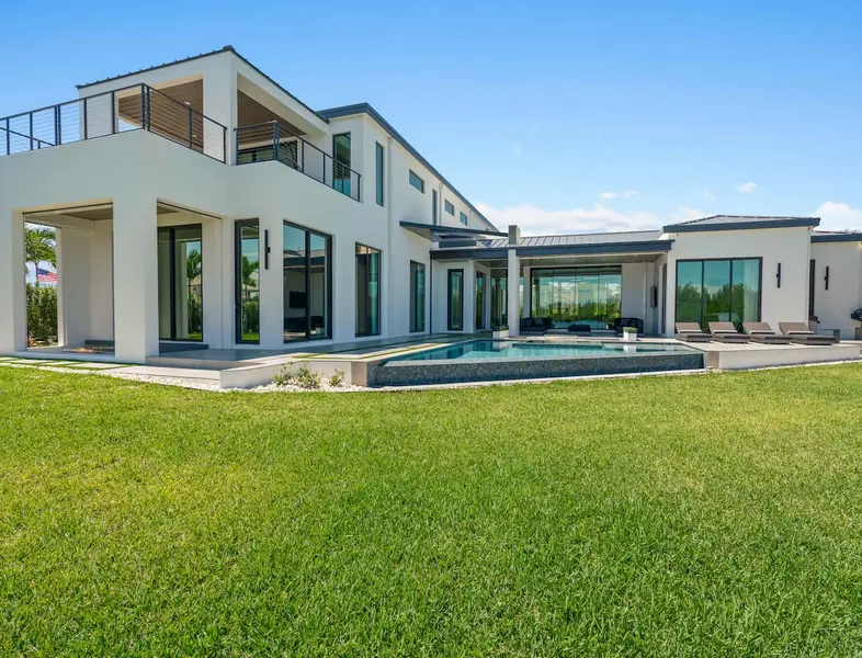 Large white house in modern design with a wide backyard and a pool.