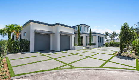 A large driveway with a white modern house and a two car garage.