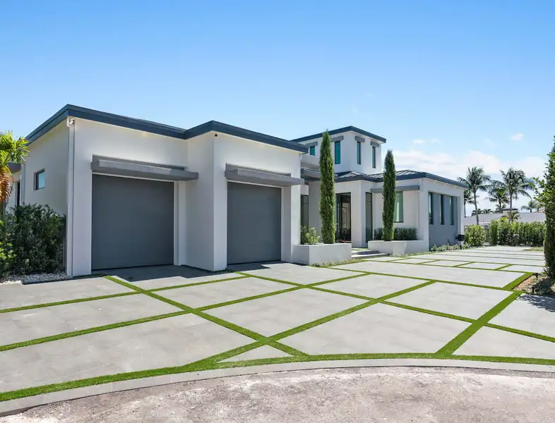 A large driveway with a white modern house and a two car garage.