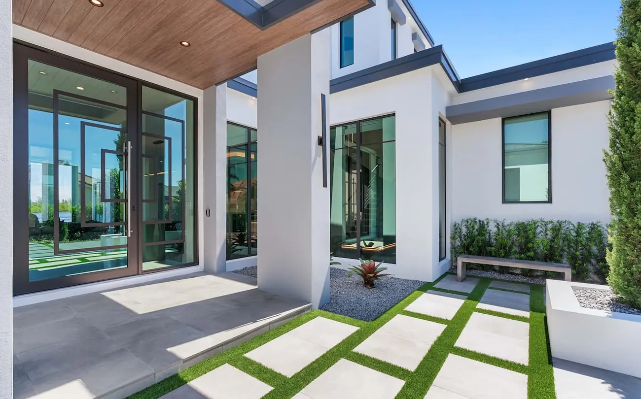 The front porch of a white modern house, glass doors and large windows.