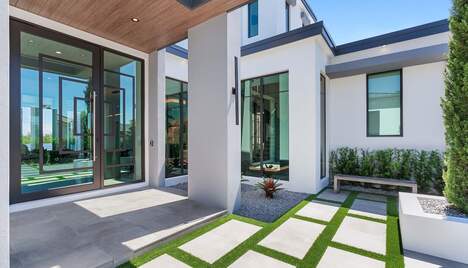The front porch of a white modern house, glass doors and large windows.