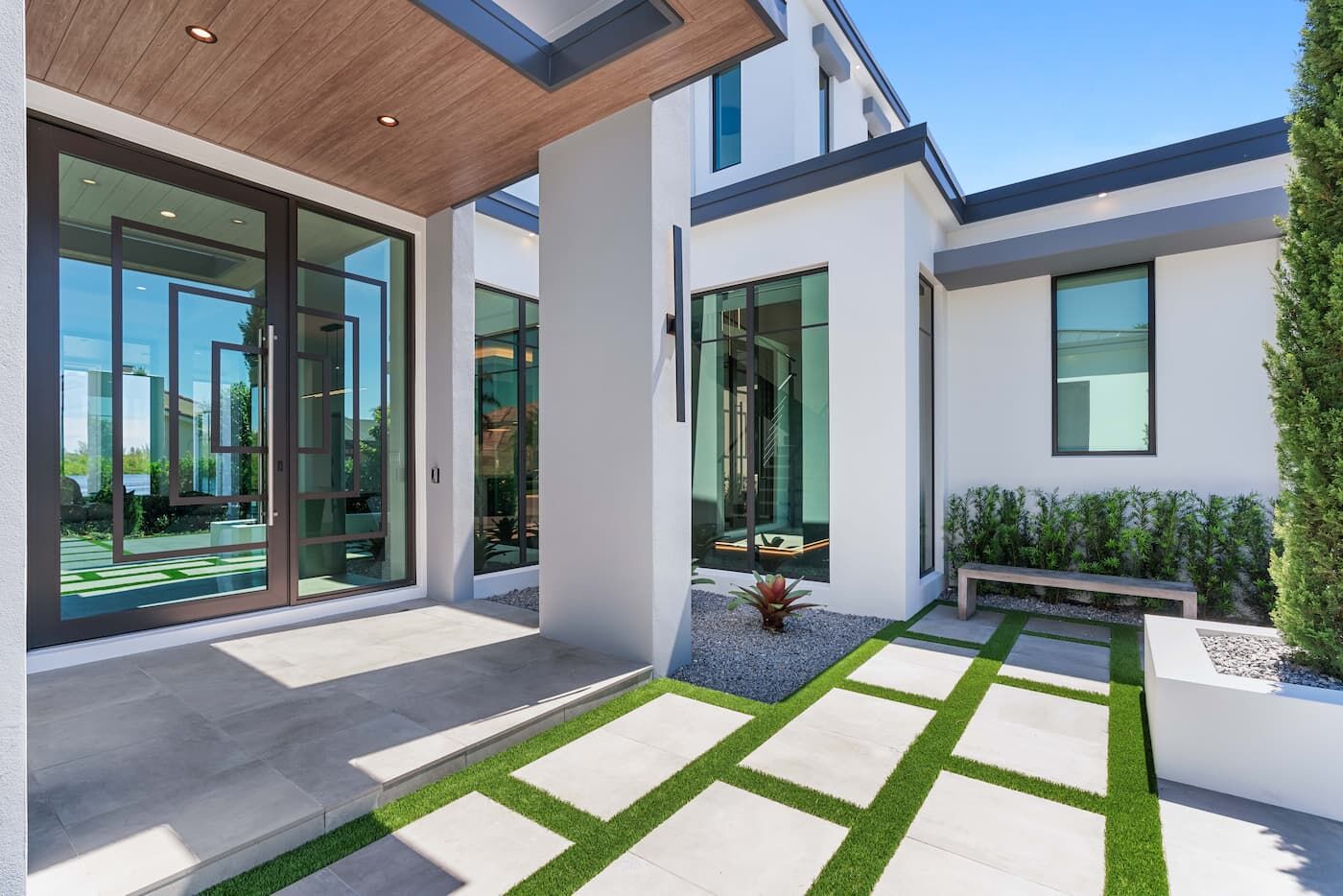 The front porch of a white modern house, glass doors and large windows.