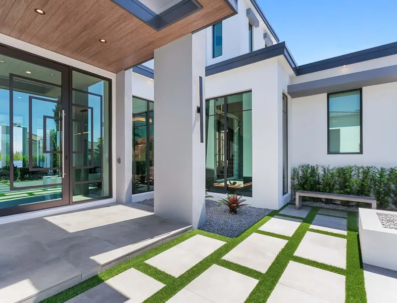 The front porch of a white modern house, glass doors and large windows.